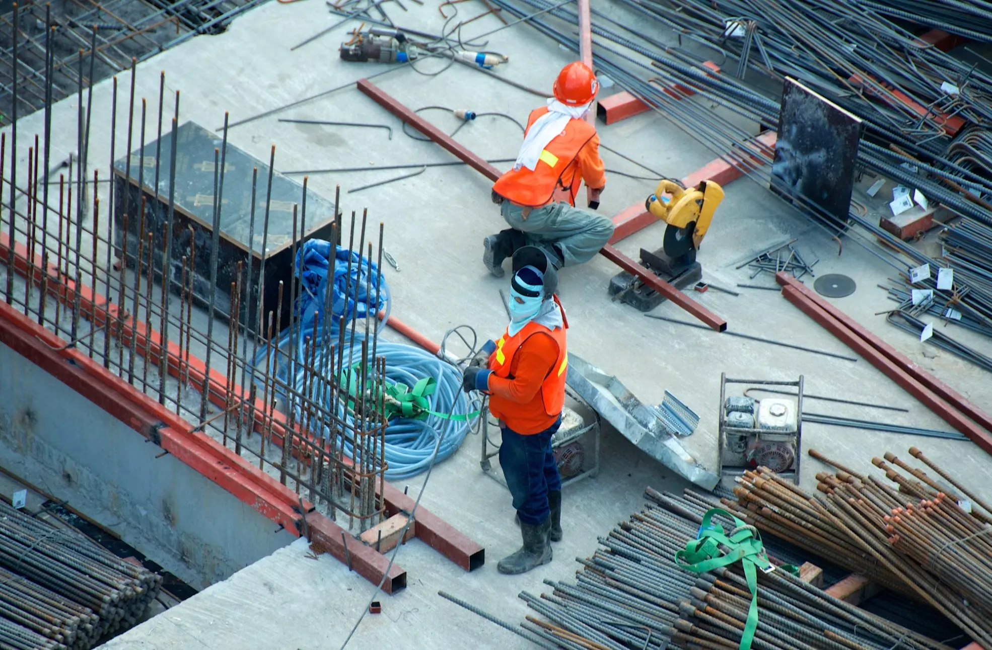 Steel fixers working on a concrete slab with power tools, hoses and a generator